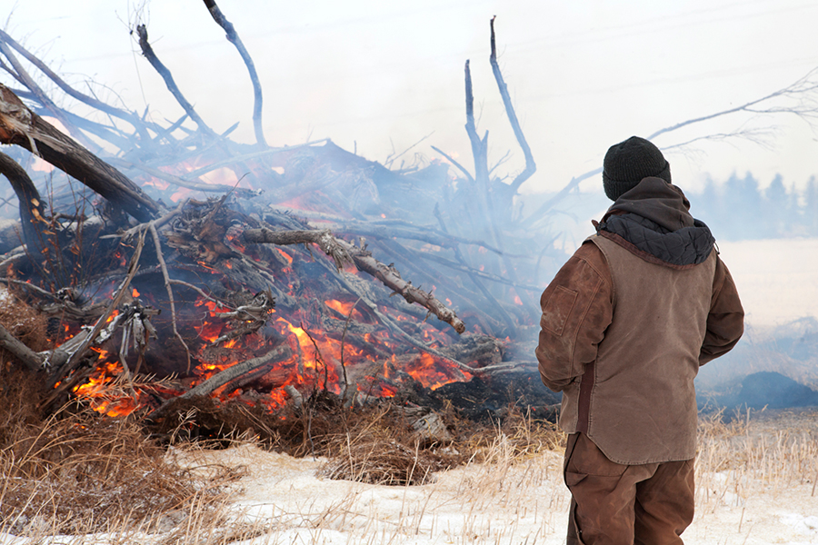 farmer burning wood pile in a snowy field