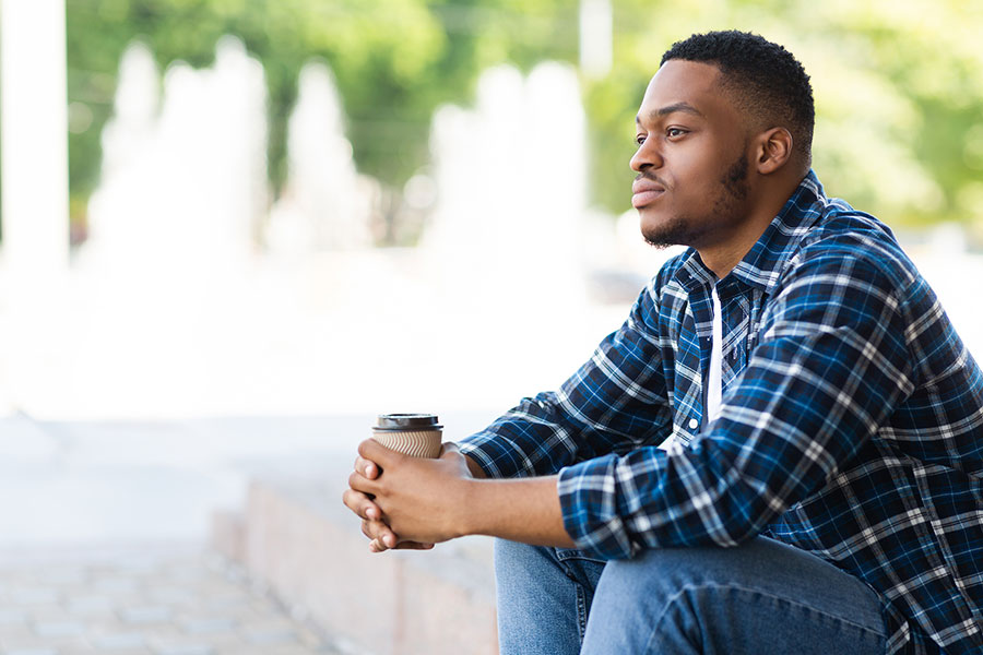 man sitting and thinking while holding a coffee cup
