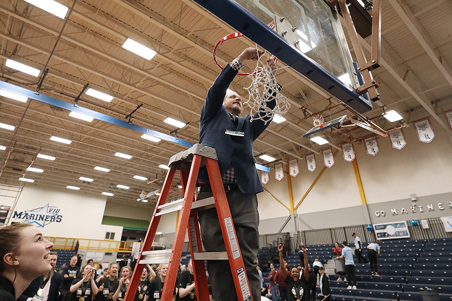 Former NAIT ooks women's basketball coach Todd Warnick cuts net from basket as a championship souvenir