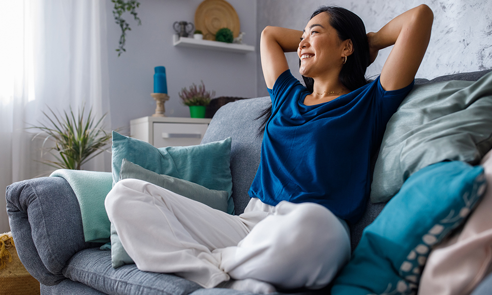 woman on a couch relaxing and smiling as she looks out a window