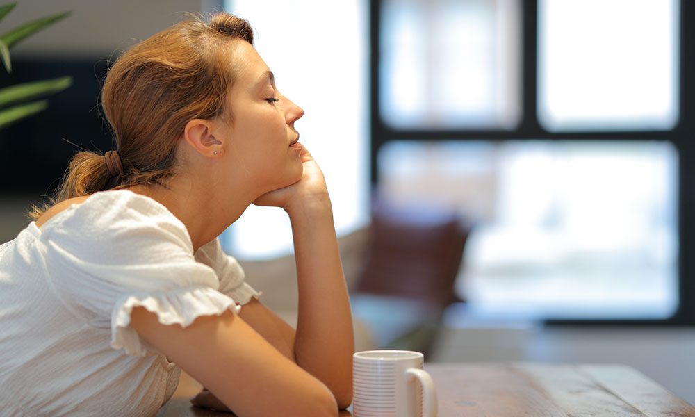 woman indoors smelling fresh air and enjoying coffee