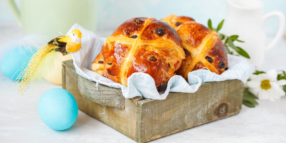 hot cross buns in a wooden box decorated with fake birds and flowers for easter