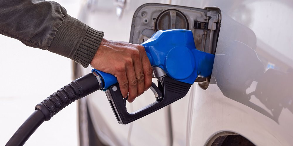 man's hand pumping gas into white car